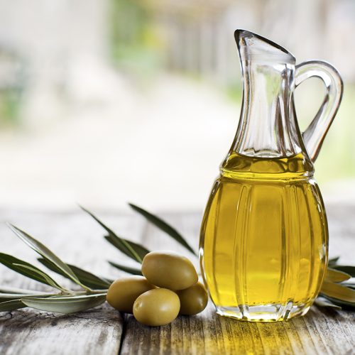Olive oil and olive branch on the wooden table outside